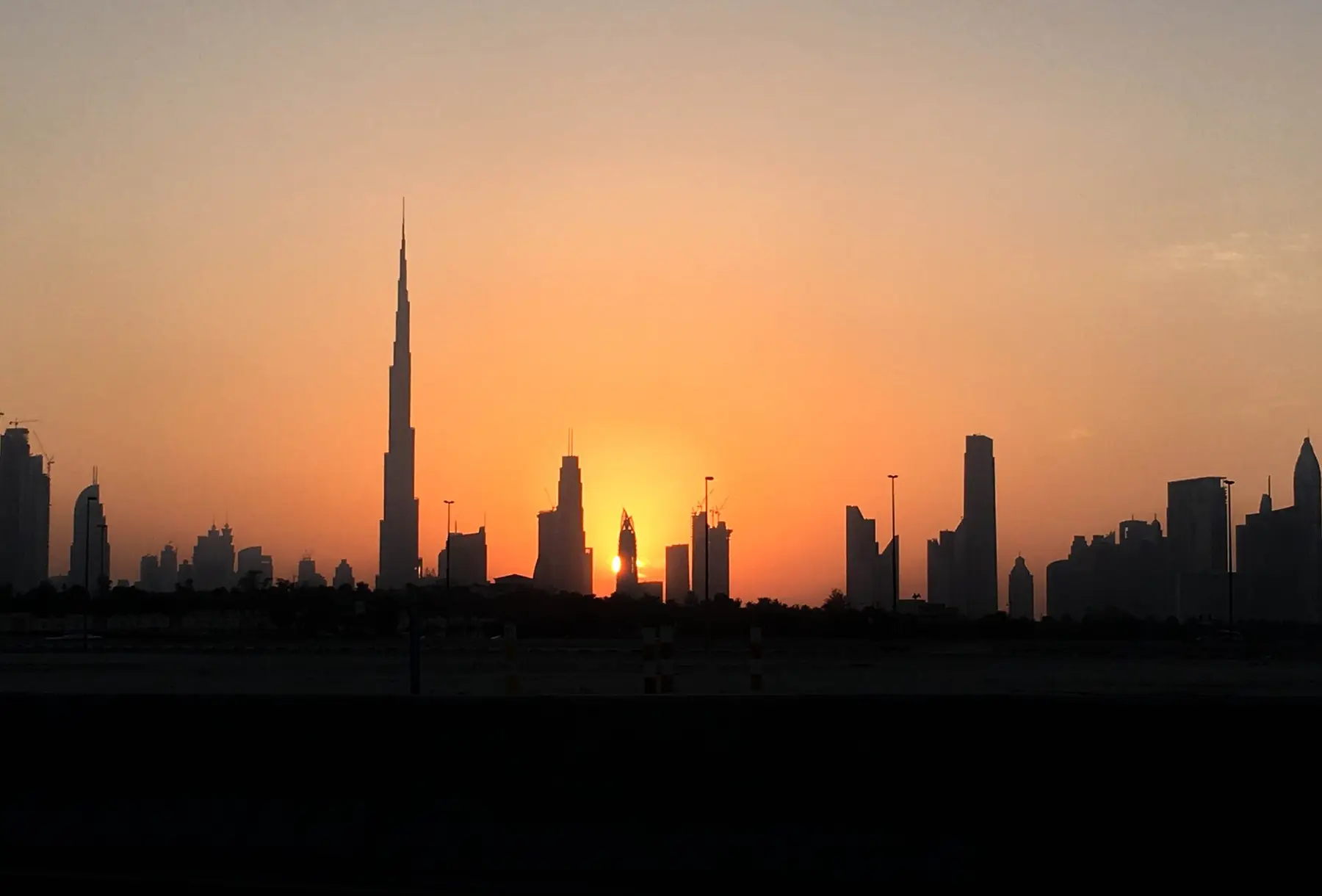 The Dubai skyline in silhouette against an orange sunset